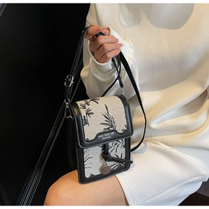 Detail of canvas and black PU leather crossbody bag featuring floral print and metal logo