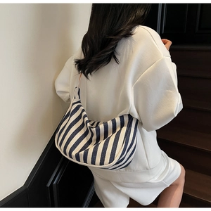 Détail du sac bandoulière en toile rayée montrant la texture et les rayures bleues