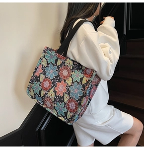 Close-up of vintage floral jacquard tote bag with black strap held by a model