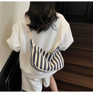 Détail du sac croissant en toile à rayures bleues et blanches avec bandoulière réglable