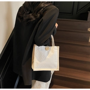 Dettaglio di una borsa tote in tela con manici in corda spessa e bottone decorativo in legno