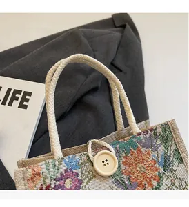 Detail of floral linen tote bag with woven rope handles and round wooden button closure