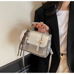 Detail view of silver metallic leather crossbody bag with golden dual buckle closures