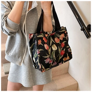 Dettaglio del tessuto jacquard con tulipani vintage e tracolla nera sulla borsa tote