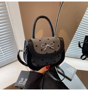 Detail of saddle bag featuring a polka dot flap and silver metal bow ornament