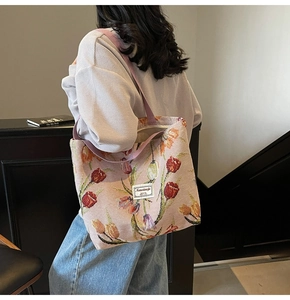 Close-up of pink woven tote bag with colorful tulip pattern and fabric shoulder strap