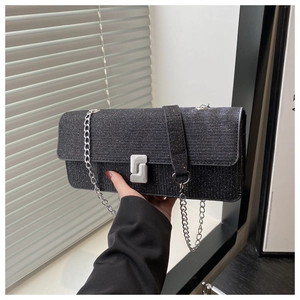 Detail shot of black glitter handbag featuring silver chain and metal buckle closure