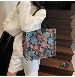 Close-up of floral embroidery texture and wide black strap on the large ethnic tote bag