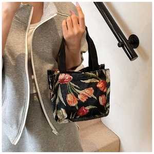 Dettaglio della borsa tote con ricami di tulipani colorati su tessuto nero materico
