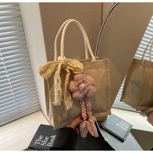 Dettaglio della borsa in juta con fiocco in pizzo e ciondolo a fiore in peluche