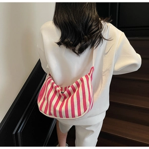 Détail du sac hobo en toile à rayures roses et blanches porté en bandoulière par un mannequin