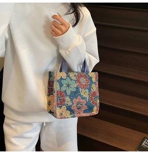 Ethnic style large tote bag with floral patterns on blue fabric shown on wooden stairs