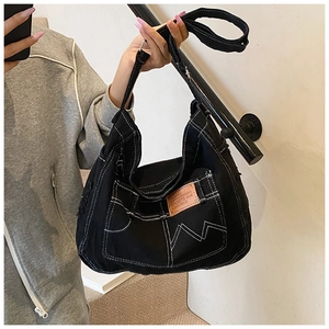 Detail of black denim tote bag with white contrast stitching and sports label