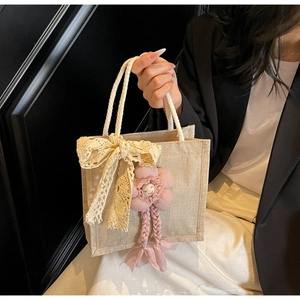 Dettaglio della borsa in iuta con fiocchi in pizzo floreale e fiori rosa decorativi