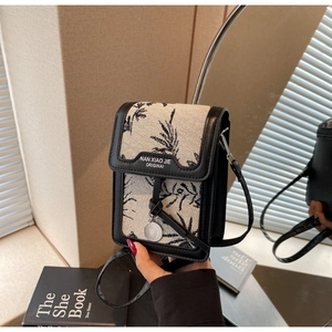 Detail of a chic canvas crossbody bag featuring black palm leaf prints and mirror reflections