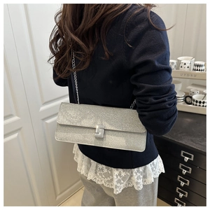Detail of silver glitter crossbody bag showing fine texture and sleek metal chain strap