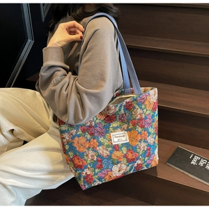 Détail du cabas à fleurs en tapisserie avec texture tissée et étiquette en tissu carrée