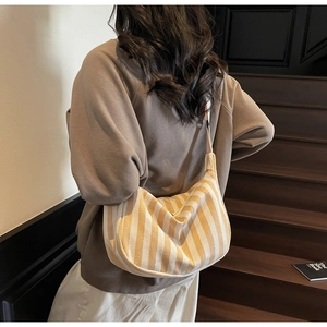 Détail du sac bandoulière en toile rayé jaune et beige sur un mannequin en situation