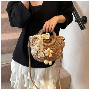 Détail du sac en paille avec nœud en dentelle, pendentif fleur tricoté et doublure