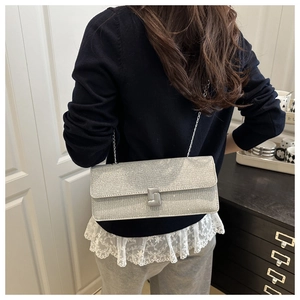 Silver glitter rectangular shoulder bag with metal chain strap and square clasp on person
