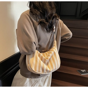 Détail du sac hobo en toile rayée jaune montrant la texture tissée et la bandoulière