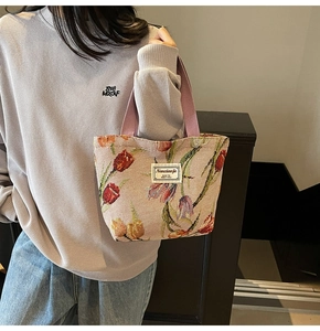 Detail of tulip embroidery on thick woven beige tote bag with purple straps and logo