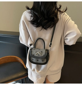 Close-up of grey wool saddle bag with black bow print and silver metal bow clasp