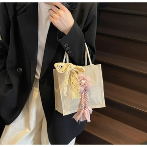 Dettaglio borsa pranzo in tela con fiocco in pizzo e ciondolo floreale rosa decorativo