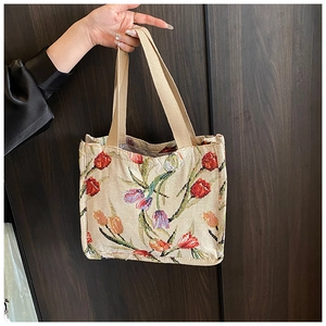 Dettaglio ravvicinato del ricamo jacquard di tulipani su una borsa tote capiente