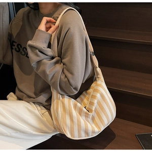 Détail du sac fourre-tout en toile rayée avec bandoulière large et fermeture éclair noire