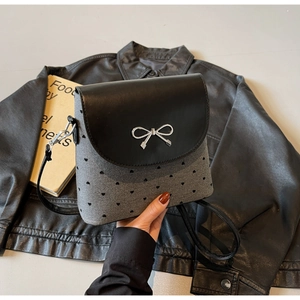 Detail of a mini flap crossbody bag with silver bow accent and heart pattern fabric