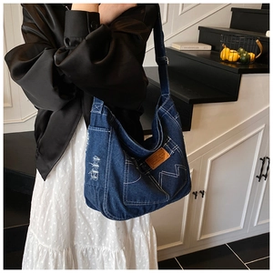 Close-up of vintage blue denim tote bag with white contrast stitching and leather patch