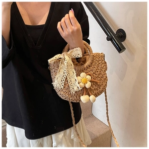Détail du sac seau en paille fait main avec nœud en dentelle et breloque fleurie