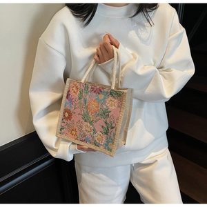 Detail of floral woven texture on a mini linen tote bag with cream braided rope handles