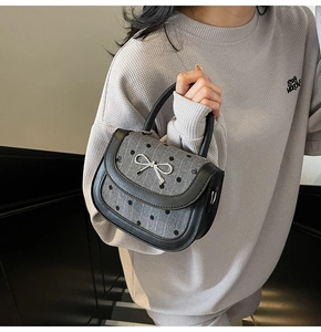 Detail of grey saddle bag with black polka dots, stripes, and silver bow hardware