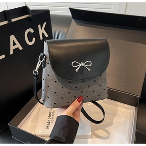 Detail view of heart-patterned canvas bag with silver bow buckle and adjustable strap