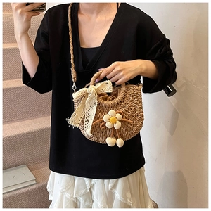 Détail du sac seau en paille avec nœud en dentelle crème et décoration de tournesol