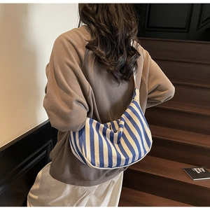 Sac hobo en toile à rayures bleu et blanc porté par un mannequin en escalier