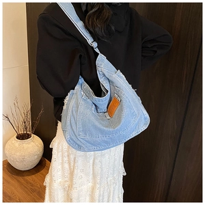 Detailed macro view of retro washed light blue denim tote bag with frayed edge finish