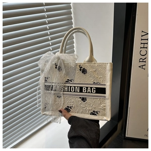 Detail of white tote bag featuring black rose jacquard and stylish lace bow decoration