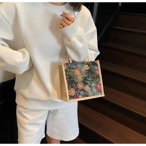Close-up of vintage floral brocade pattern on a square linen tote bag held by a model