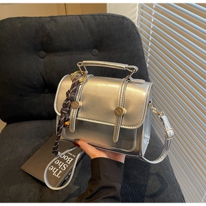 Detail of silver metallic vintage crossbody bag with mirror finish and woven pendant