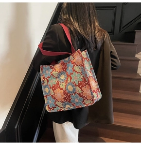 Detailed macro view of large ethnic floral tote bag with textured red jacquard fabric