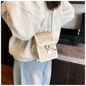 Detail of beige crossbody bag with floral embossing and pearl chain strap decoration