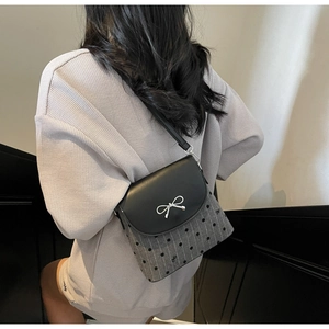 Detail view of the silver bow buckle and polka dot fabric on the trendy crossbody bag