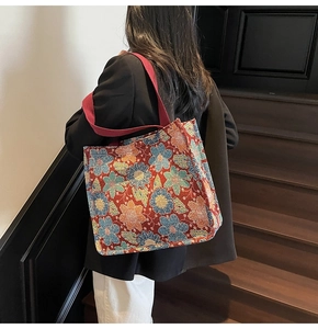 Detailed close-up of large floral jacquard tote bag with vibrant ethnic patterns and red straps