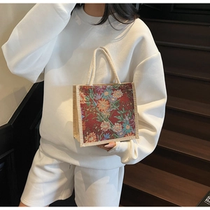 Linen lunch tote bag with red floral embroidery and cotton rope handles shown on a model