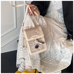 Detail of vintage beige mini crossbody bag with jacquard floral pattern and pearl charm