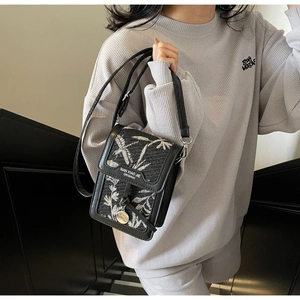 Detailed view of jacquard crossbody bag with leather trim on model in a stairwell