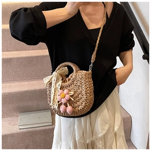 Détail du sac à bandoulière en paille avec nœud en dentelle et fleur tricotée sur modèle